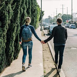 A picture of a man and woman holding hands while walking